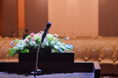 Microphone standing on a  table with flower bouquet in the meeting roomの写真素材