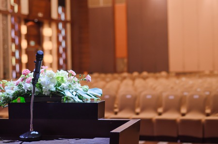 Microphone standing on a  table with flower bouquet in the meeting roomの写真素材