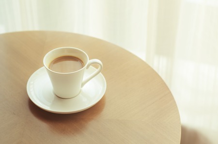 Coffee cup on wood table with vintage blur filter effectの写真素材