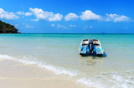 Seascape in the summer with a boat against sand beach and blue sky.の写真素材