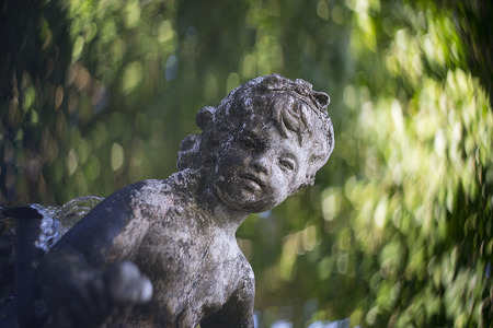Selective focus Cupid Statue in green gardenの写真素材