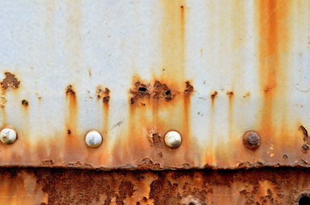 Rusty corrugated iron plate with rivets on it.の写真素材