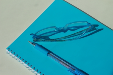 Notebooks, pens, glasses in blueの写真素材