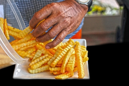 Male hand holding French fries fried.の写真素材