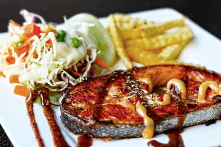 Salmon steak and french fries and salad.の写真素材