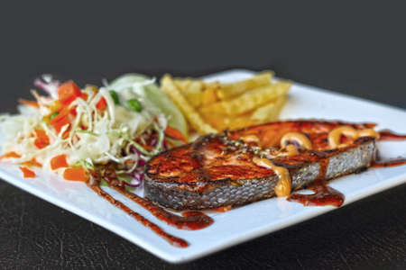 Salmon steak and french fries and salad.の写真素材