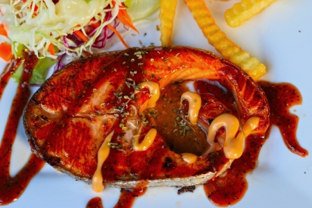 Salmon steak and french fries and salad の写真素材