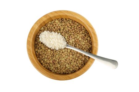 wood bowl with raw lentil and spoon with rice isolated on whiteの写真素材