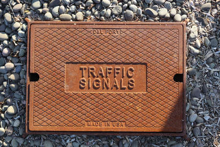 Grunge metal sewer hatch on pebble beach with inscriptionの写真素材