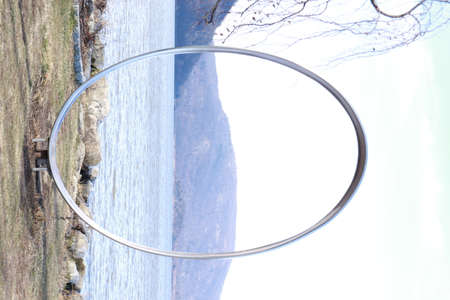 Circular metal ring on the background of the lake and the skyの写真素材