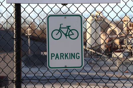 Bike parking sign on a chain link fence in front of a buildingの写真素材