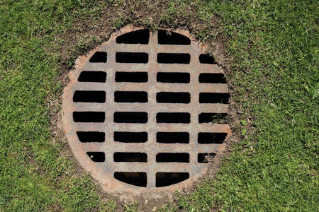 Drainage hatch on the grass in the park, top viewの写真素材