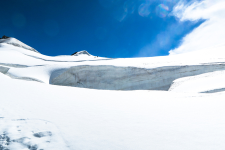 Mountain climbers walking on the glacier near the crack. View to the Berelskoe sedlo glacier. Belukha Mountain area. Altaiの写真素材
