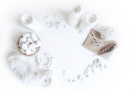 Boho white mockup with candles, cotton yarn, feathers and white sea pebble on the desk. Top view flat lay. Space for textの写真素材