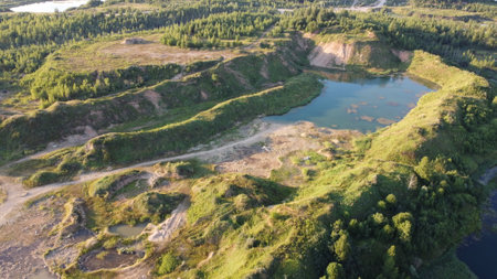 Flooded and overgrown sand quarry. Lush green summer landscape for outdoors vacation, hiking,...