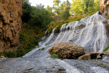 Jermuk waterfall flowing stream picturesque view among the canyon rocks sunlit gorge. Armenian stock...