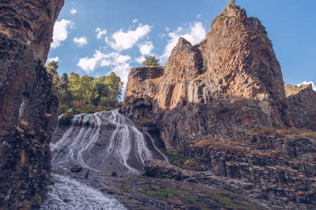 Jermuk waterfall flowing stream picturesque view among the canyon rocks sunlit gorge. Armenian stock...