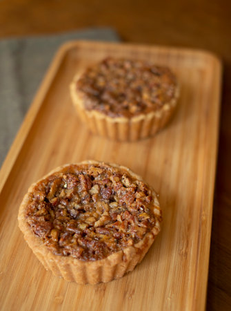Tartlets with pecan nuts on a bamboo wooden board, selective focusの写真素材