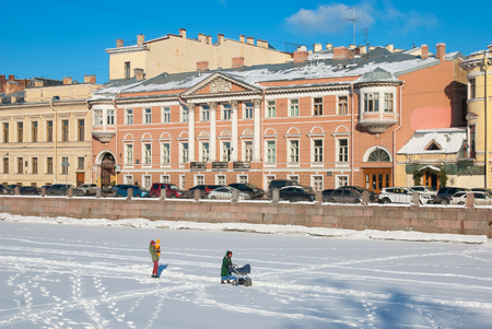 SAINT - PETERSBURG, RUSSIA - FEBRUARY 24, 2018: Young people with a baby and a pram on the frozen ice The Fontanka Riverのeditorial素材