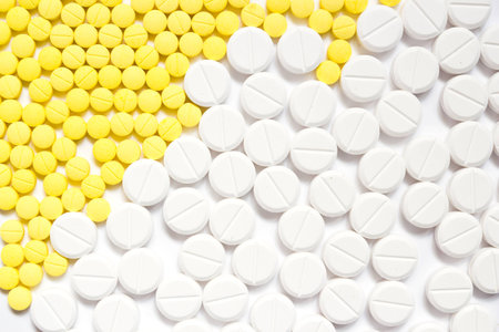 Yellow and white pills on white background with shadowの写真素材