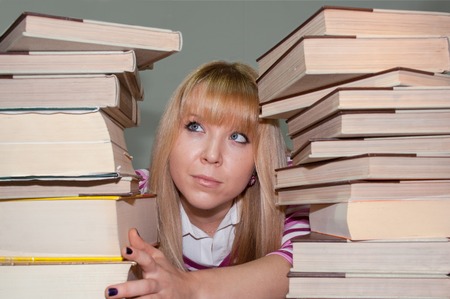 young female student has too many books to read for examsの写真素材