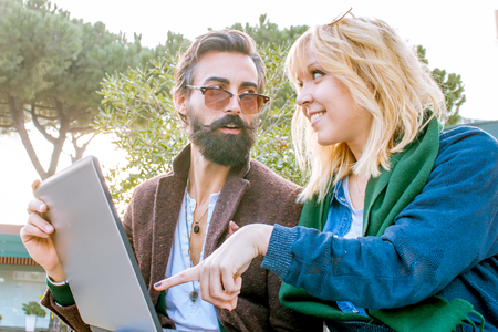 young woman and man with laptop computer working together outdoors - concept of start up team enjoying teamworkの写真素材