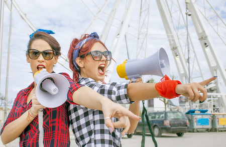 female protesters rally shouting political slogans with megaphone loudspeakers wearing redの写真素材