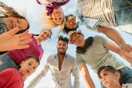 cute kids with parents and friends in a circle looking down for photo. young diverse parents with cute children enjoying together on a day out. ultra wide angle viewの写真素材
