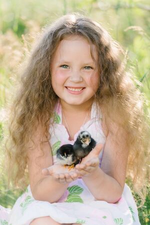 Little girl having fun playing with duck or chicken. Toddler kids outdoor. Happy child laughing and smiling.の写真素材