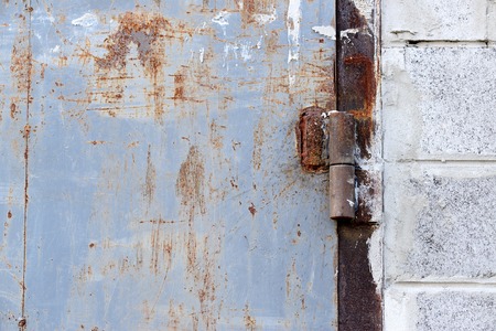 Rusty scratched grunge damaged metal wall with gate hingers detailed texture backgroundの写真素材