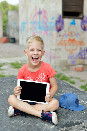 Child with tablet PC in the street. Boy holding computer outdoors in the city. Childhood, education, learning, technology, leisure conceptの写真素材