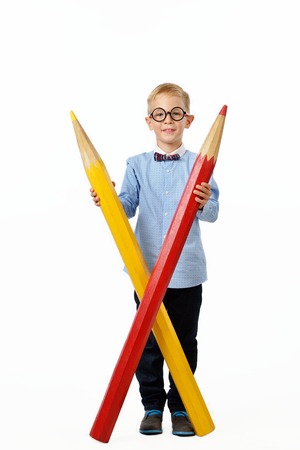 Happy boy in glasses and bowtie posing full length with a huge pencil. Educational concept. Isolated over white. School preschoolの写真素材