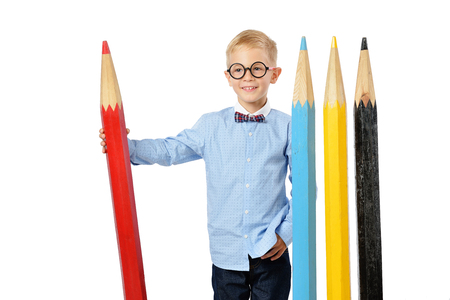 Laughing boy in glasses and bowtie posing with a huge pencils. Educational concept. Isolated over white. School preschoolの写真素材