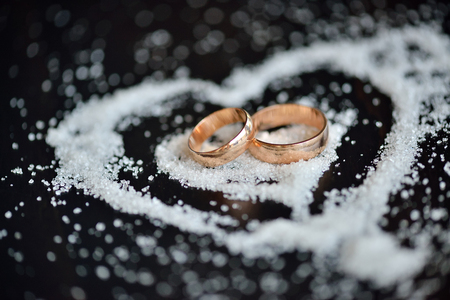Wedding gold rings in sugar heart on dark wooden background. Valentine's day, engagement event, loveの写真素材