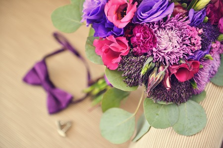 Beautiful Wedding purple Bouquet with brooch and groom bowtie cufflinks on beige chair. Background, floristic compositionの写真素材