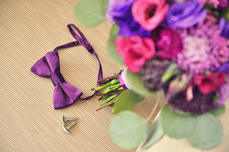 Beautiful Wedding purple Bouquet with brooch and groom bowtie cufflinks on beige chair. Background, floristic compositionの写真素材