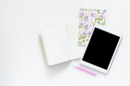Flat lay photo of office white desk with tablet and open notebook copy space backgroundの写真素材
