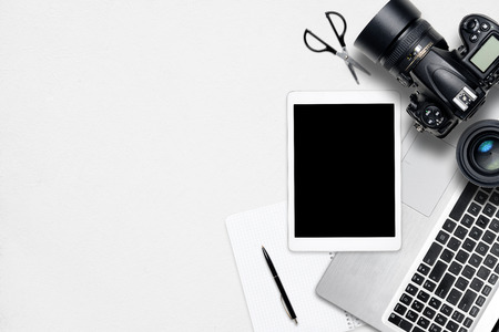 White office photography desk table with laptop, tablet, camera and glass. Top view with copy spaceの写真素材