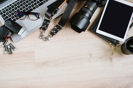 Photography hipster work table set with computer, tablet, film, lenses, supplies and camera. Top...