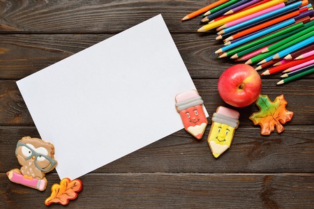 Back to school concept background with colored pencils, red appple and gingerbread on wooden table,...