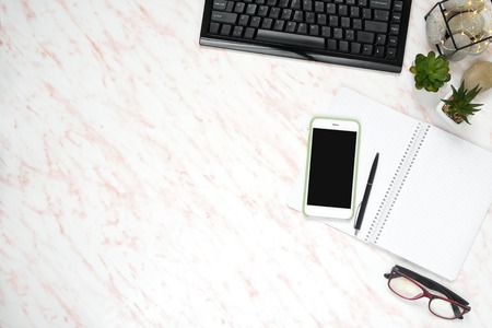 Flat lay office marble desk with phone, keyboard and notebook copy space background. Mock up...