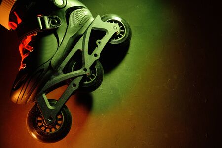 Close up view of roller skates inline skate or rollerblading on dark grunge background in neon...