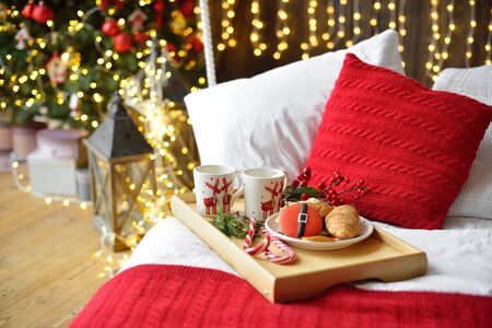 breakfast in bed, tray with cup of coffee and croissant. Modern bedroom interior. Romantic morning surprise. Christmas moodの写真素材