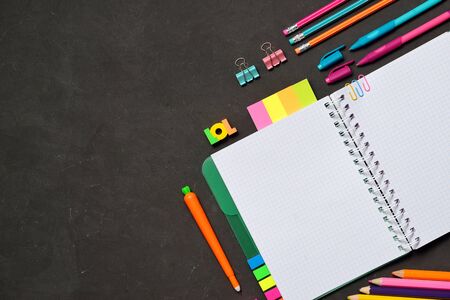 Back to School concept - open copy book with office and student supplies on black chalk background. Space for text. Flat layの写真素材