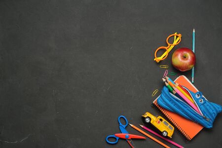 Back to School concept - office and student supplies on black chalk background. Space for text. Flat...
