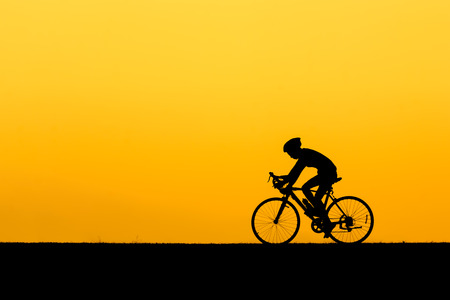 A silhouette of man cycling on the lawn in sunset.の写真素材
