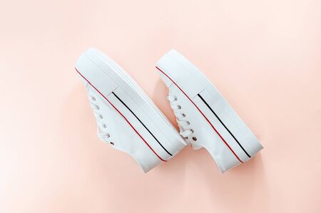 White trendy white sneakers on creamy peach background. Flat lay, top view, shoe side. Place for text. Minimalistic style composition. Sports wear, active lifestyle concept.の写真素材