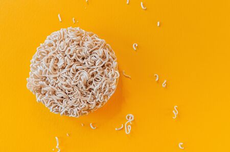 Dry noodles on bold yellow background with space for text. Asian fast food horizontal flat lay. Bright minimalistic style photography.の写真素材