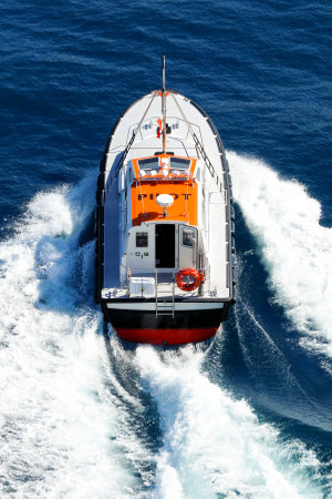 A pilot boat powerfully navigates in a blue sea, leaving a big white foam behind it のeditorial素材