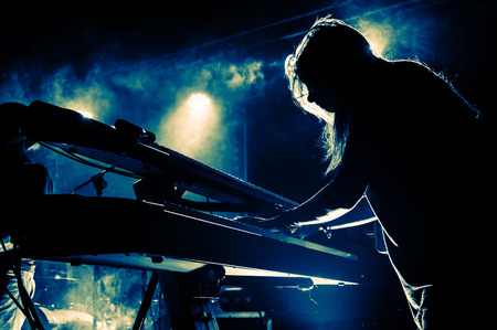 Female keyboards player on stage during concert, backlight, colors intentionally alteredの写真素材